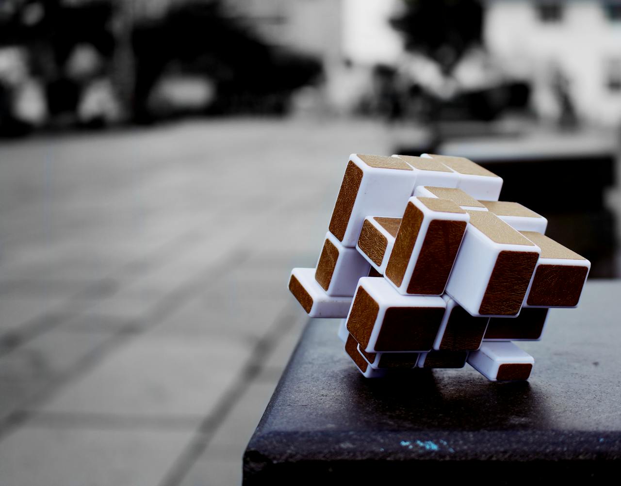 Artistic cube puzzle placed on a surface in an urban setting, capturing depth and focus.